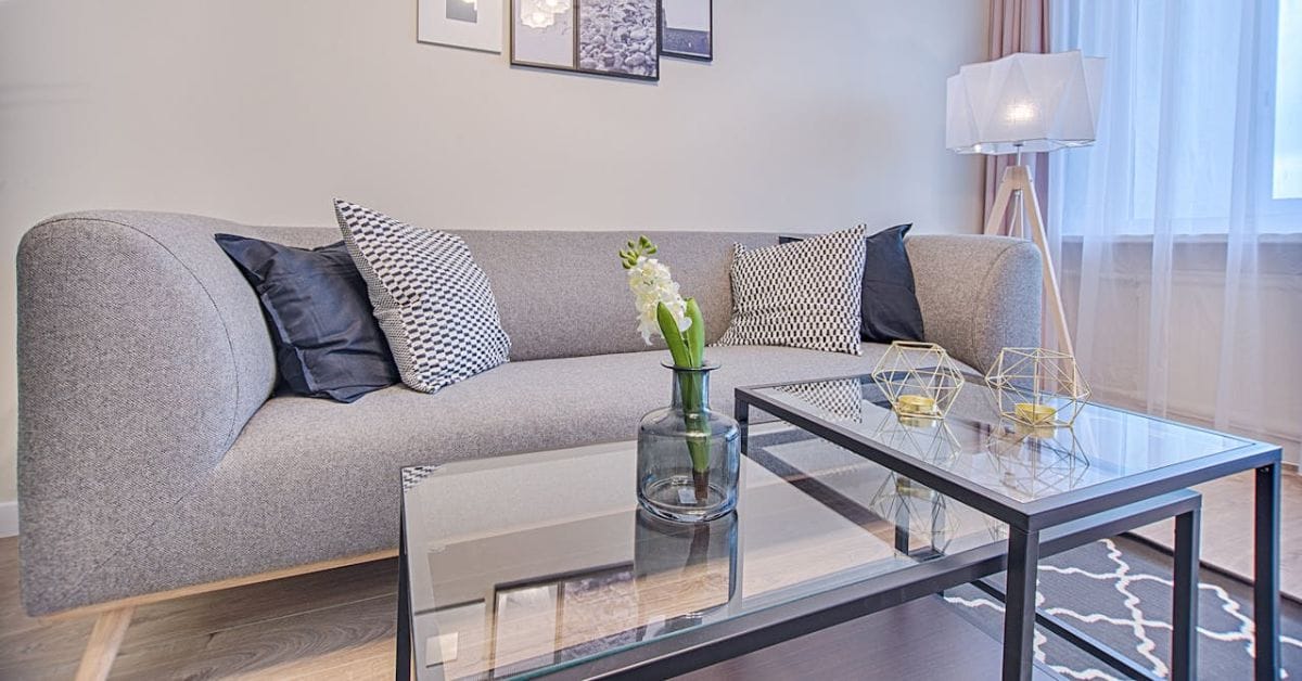 Stue med grå sofa og glasbord